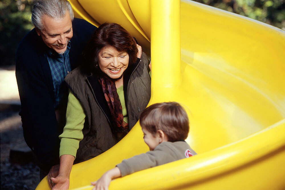 Boy going down a slide with parents