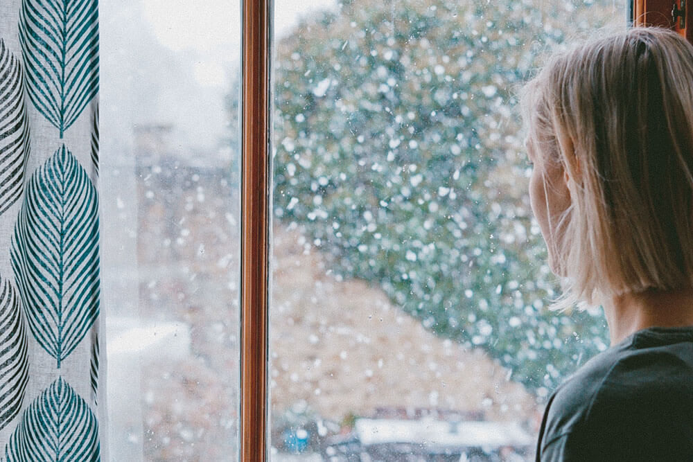 Woman looking out window at snow